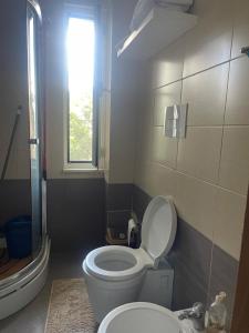 une salle de bain avec toilettes, lavabo et fenêtre dans l'établissement Apartament In Lalzi Bay, Lura 1 Complex, à Draç