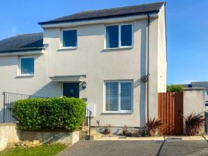 a white house with blue windows and a fence at Blissful Ocean Breeze in Perranporth