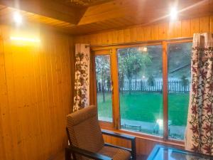 Cette chambre dispose d'une fenêtre avec une chaise et une table. dans l'établissement River Retreat Resort, à Pahalgām