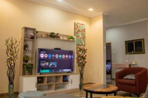 a living room with a flat screen tv and a chair at FranGee gold house with cool breeze & solar backup in Kpomkpo
