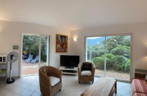 a living room with a table and chairs and a television at Maison récente entre mer et montagne in Figari