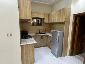 a kitchen with wooden cabinets and a stainless steel refrigerator at Comfort Stay Apartments Cadjehoun in Cotonou +2 photos