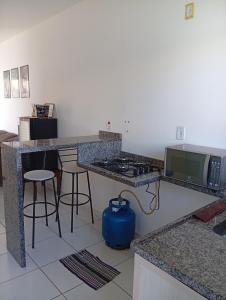 a kitchen with a stove and a counter with stools at Casa de férias Pôr do Sol in Presidente Epitácio