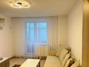 a living room with a couch and a large window at Apartament Tomis Nord in Constanţa