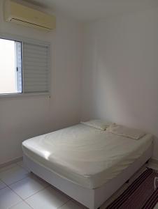 a bed in a white room with a window at Casa de férias Pôr do Sol in Presidente Epitácio