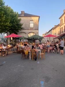 a group of people sitting at tables with umbrellas at Les Papillons in Verteillac