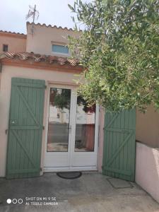une paire de portes vertes sur une maison dans l'établissement A quelques pas de la mer, à Saint Cyprien Plage