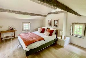 a bedroom with a bed and a desk and two windows at La Sénéchalerie in Chasselay
