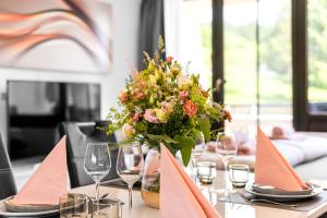 a table with a vase of flowers and wine glasses at Ferienwohnung Harmonie mit Pool in Sankt Englmar