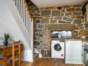 une cuisine avec lave-linge et sèche-linge à côté d'un mur en pierre dans l'établissement Dalton Cottage, à Penzance