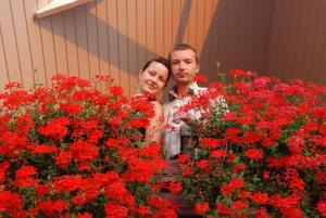 a man and a woman standing next to red flowers at Polychko Winehouse in Vynohradiv