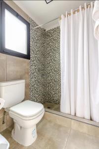 a bathroom with a toilet and a shower curtain at El Filo Aparts de Montaña in El Chalten +28 photos