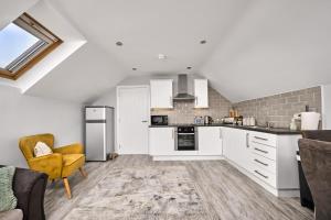 an open kitchen with white cabinets and a yellow chair at Mc Callstown House Apartment in Ballyclare