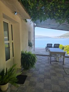 a patio with a table and a view of the water at Apartmani Nikolić "Na pjeni od mora" in Tivat