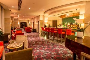 a hotel lobby with a bar and red chairs at Maritim Antonine Hotel & Spa in Mellieħa