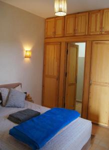 a bedroom with a bed with blue sheets and wooden cabinets at The Little Beach Cottage in Sidi Kaouki