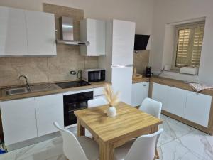 a kitchen with a wooden table and white cabinets at A Casa Do Paisi - Realmonte in Realmonte +13 photos
