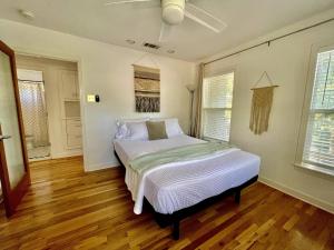 オースティンにあるDeep Eddy 2/1 Bungalow + Fenced Yard!のウッドフロアのベッドルーム1室(白いシーツ付きのベッド1台付)
