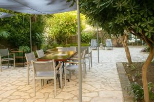 a patio with a table and chairs under an umbrella at Verdant Escape Corfu in Corfu +14 photos