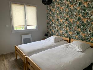 two twin beds in a bedroom with a floral wallpaper at Maison cosy à Fronton in Fronton