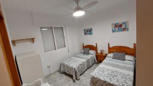 a bedroom with two beds and a ceiling fan at Apartamento Playa La Calica in San Juan de los Terreros