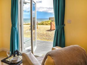 a room with a view of the beach through the sliding glass door at The Seas Beach House in Bacton