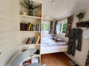 a tiny house with a bed and books at Bell Nook- Shepherd's hut with a spacious wood-fired hot tub in Tonbridge