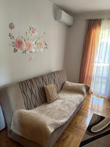 a couch in a living room with a flower picture on the wall at Elena Apartment in Plužine