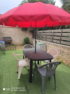 une table et des chaises avec un parasol rouge dans l'établissement A quelques pas de la mer, à Saint Cyprien Plage