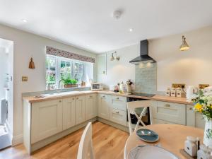 a kitchen with white cabinets and a table at Courtyard Cottage in Reeth