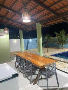 einen Holztisch und Stühle auf einer Terrasse mit einem Pool in der Unterkunft Casa Maju in Aquiraz