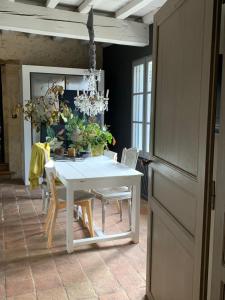 a white dining room table with chairs and a chandelier at Clos de la Besnardière in Tabanac
