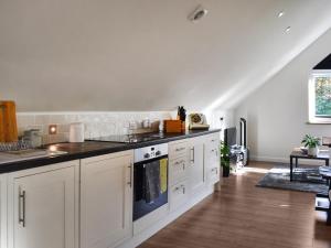 a kitchen with white cabinets and black counter tops at Garden Studio in St Austell