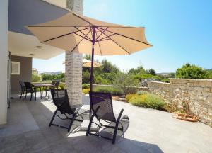 a patio with a table and a large umbrella at Murter - New apartment near Podvrske beach in Murter +11 photos
