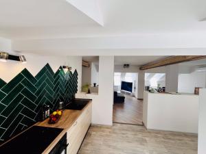 a kitchen with a black counter top and a living room at The Mountain Sky Apartment - prostorný loft 212 m2 s lesem za okny vhodný pro rodiny s dětmi, terasa, dětský koutek, parkování zdarma in Jeseník
