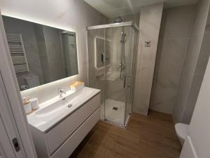 a white bathroom with a shower and a sink at Apartamentos DALA in Madrid