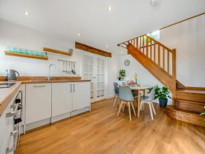 a kitchen with white cabinets and a table with chairs at Horseshoe Cottage - Uk48252 in Downderry