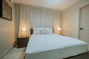 a bedroom with a large white bed and two lamps at 2 BR cozy apartment 3 minutes to Downtown Punta Cana in Punta Cana