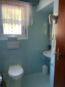 a bathroom with a toilet and a sink and a window at Casa Balwin in Ponte Tresa