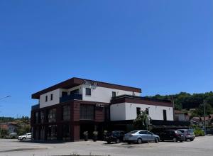 a building with cars parked in a parking lot at Apartmani Mila Mi in Kotor-Varoš