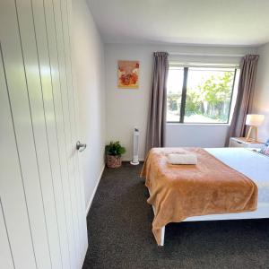 une chambre avec un lit et une fenêtre dans l'établissement Your Cosy Sunny Cove near Travis Wetlands, à Christchurch