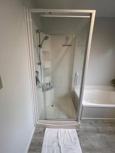 une douche avec une porte vitrée dans une salle de bain dans l'établissement Your Cosy Sunny Cove near Travis Wetlands, à Christchurch