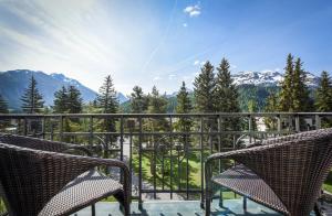 a balcony with two chairs and a view of mountains at Cresta Palace Celerina in Celerina