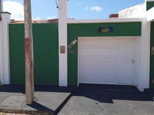 a green and white building with a garage at Casa MD in Camocim