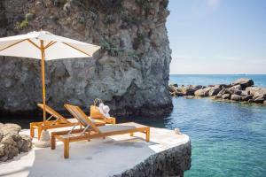 two lounge chairs and an umbrella on a beach at Pagoda Lifestyle Hotel in Ischia