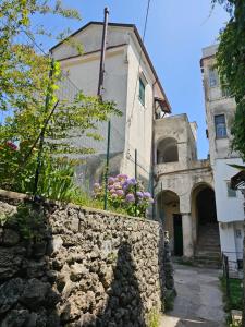 a stone wall in front of a building with flowers at Blue Sunset in Ravello