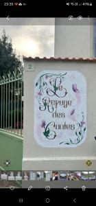 ein Schild an der Seite eines Gebäudes mit Blumen darauf in der Unterkunft Maison 15 minutes de Disney le refuge des contes Parking gratuit Wifi in Mareuil-lès-Meaux