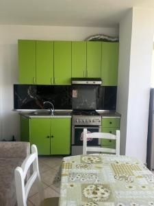 eine Küche mit grünen Schränken, einem Tisch, einem Tisch und Stühlen in der Unterkunft The Soft Pines Escape in Golem