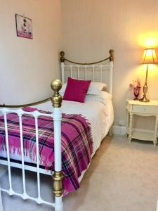 a bedroom with a white bed with a purple blanket at Storrs Gate House in Bowness-on-Windermere +121 photos