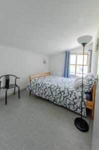 ein Schlafzimmer mit einem Bett, einer Lampe und einem Stuhl in der Unterkunft Gîte Les Galinettes en Ardèche in Saint-Martin-le-Supérieur